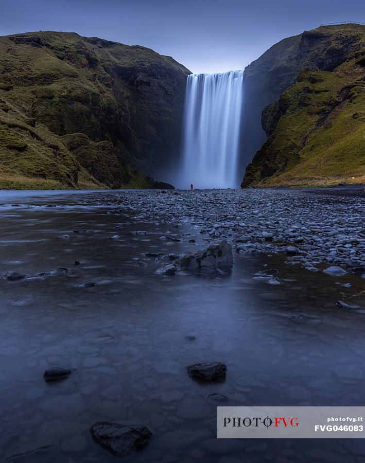A person standing in front of Skgafoss waterfall in Iceland, Europe